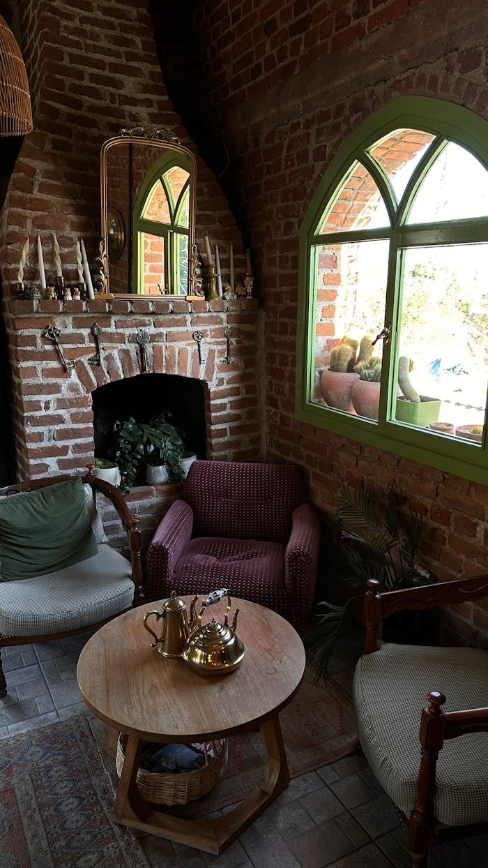 Warm, rustic indoor setting featuring brick fireplace, cozy chairs, and vintage decor.