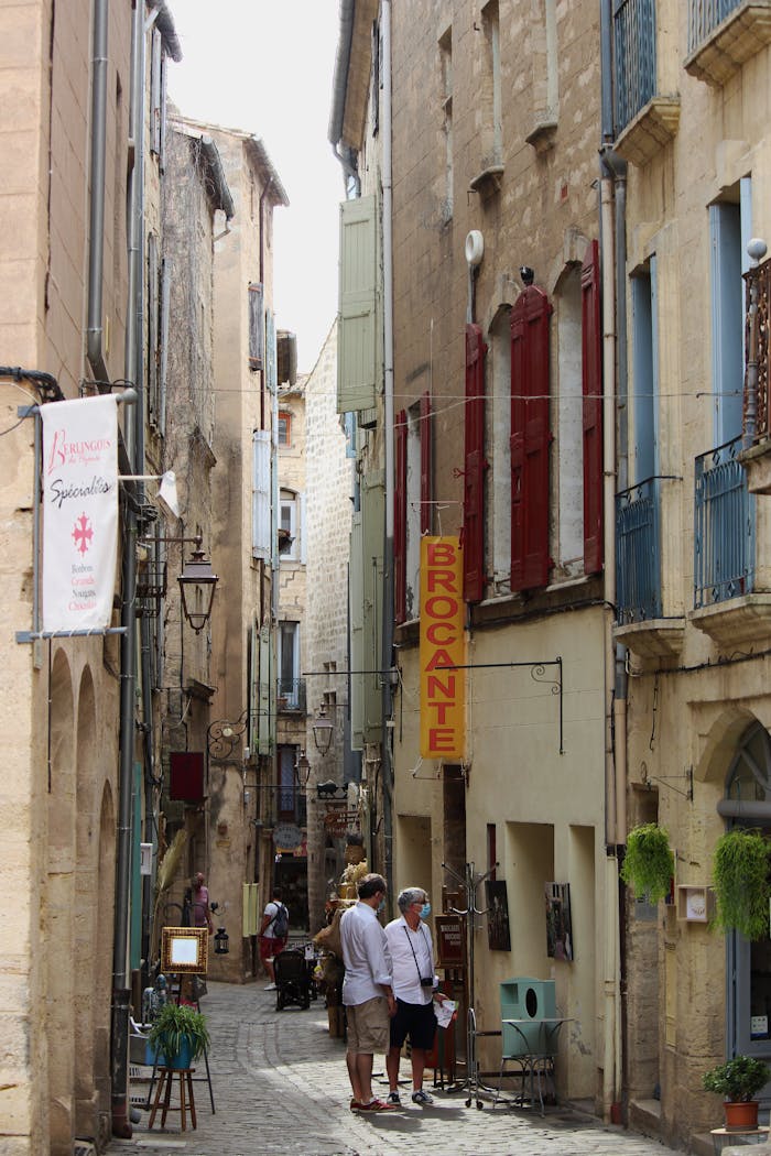 Picturesque European alley with historic buildings, shops, and people on a sunny day.